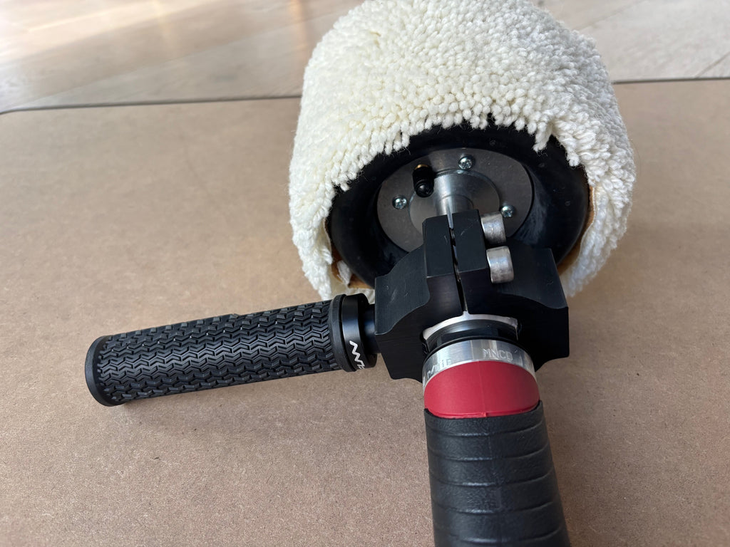 Lucid Aero drum buffer front-end view showing mounting clamp, two hex socket bolts, grip handle, and partial wool sleeve
